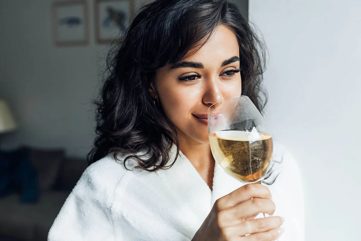Smiling Woman Drinking Wine While Standing At Home