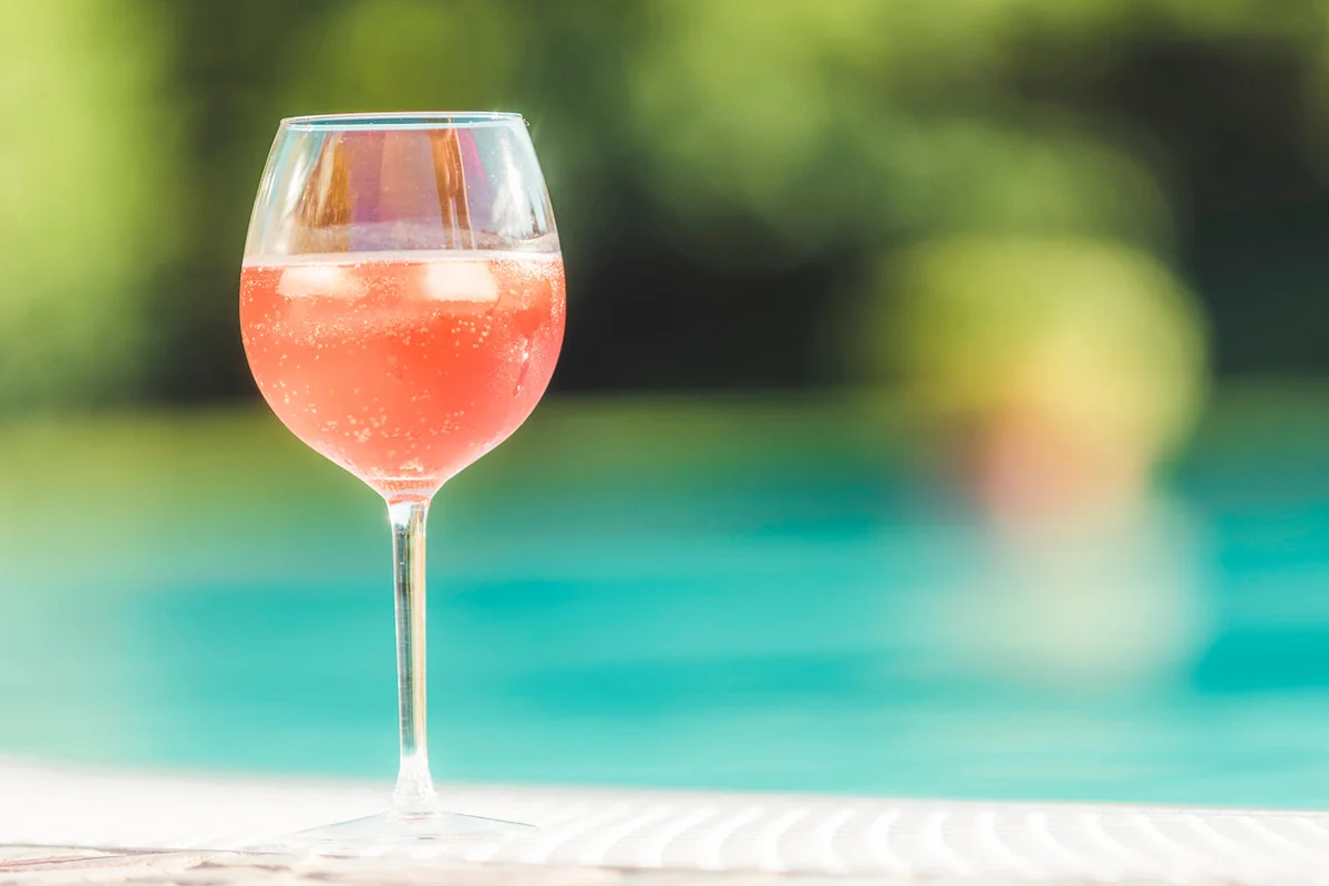 Close up of a drink with a luxury pool in the background