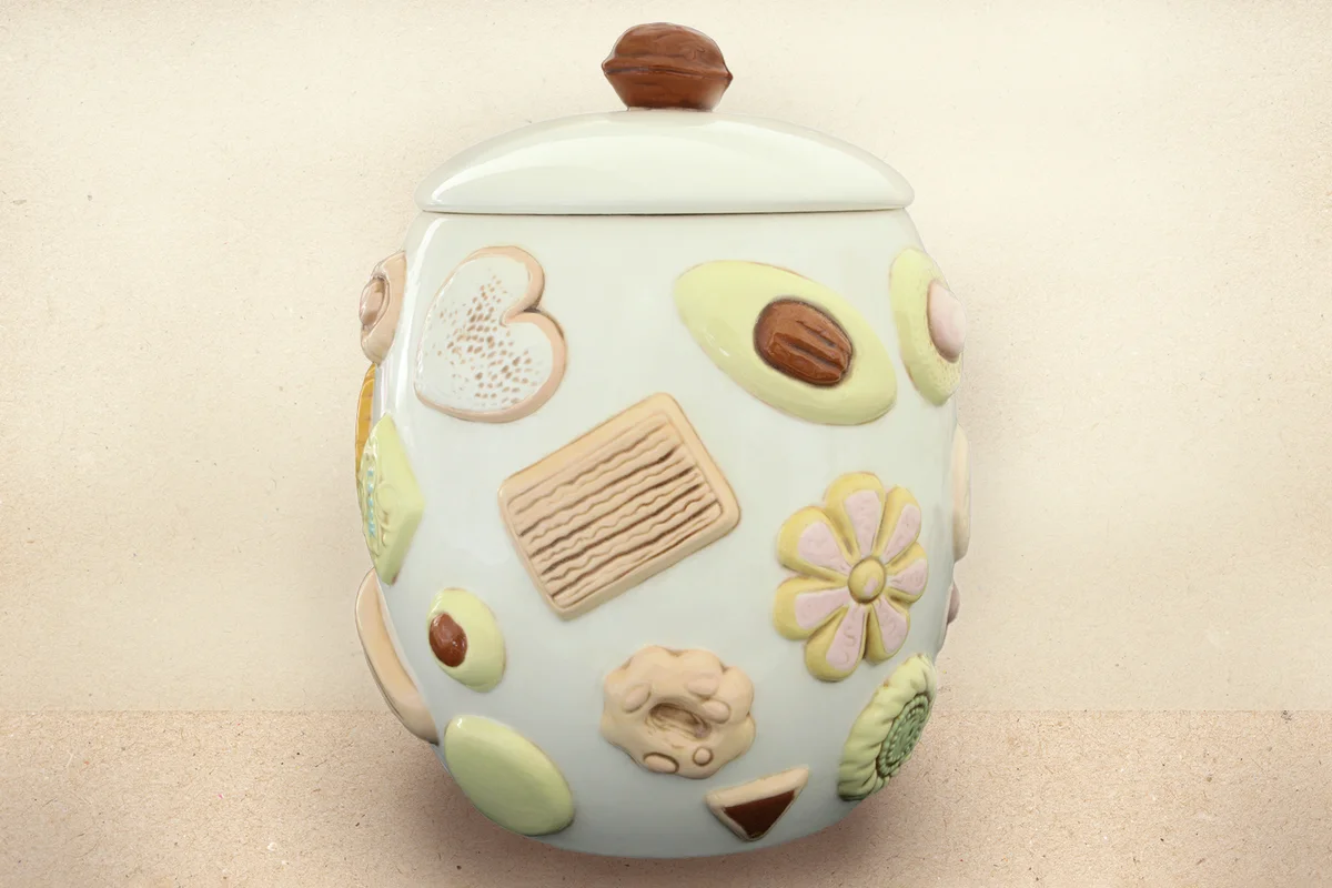 A vintage moulded ceramic cookie jar decorated with 3D cookies and a walnut shaped handle