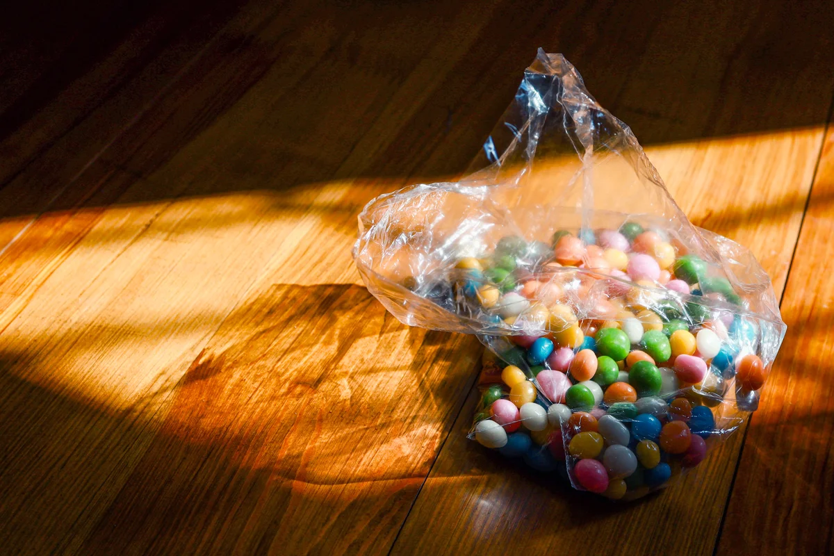 Plastic bad with jelly beans on wooden surface