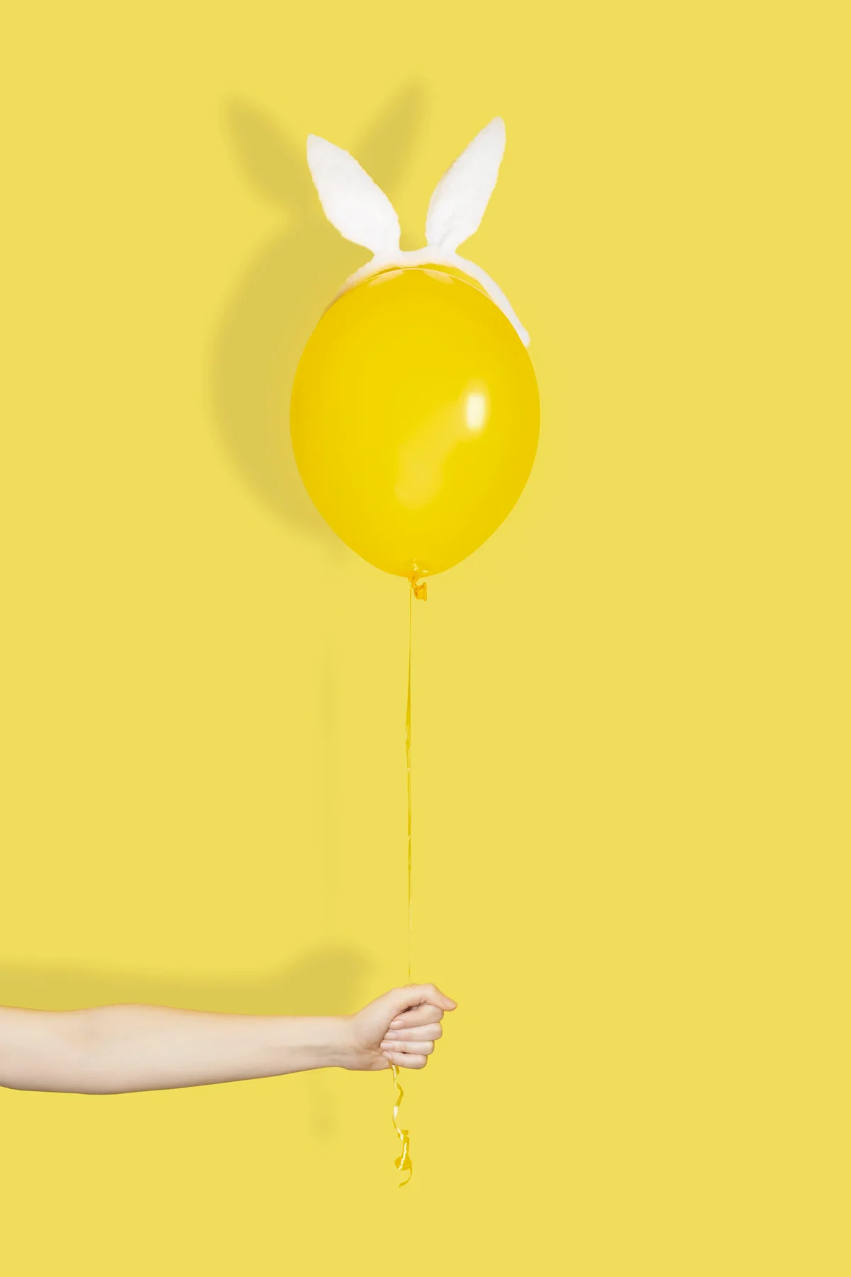 Hand holding a yellow balloon in bunny ears