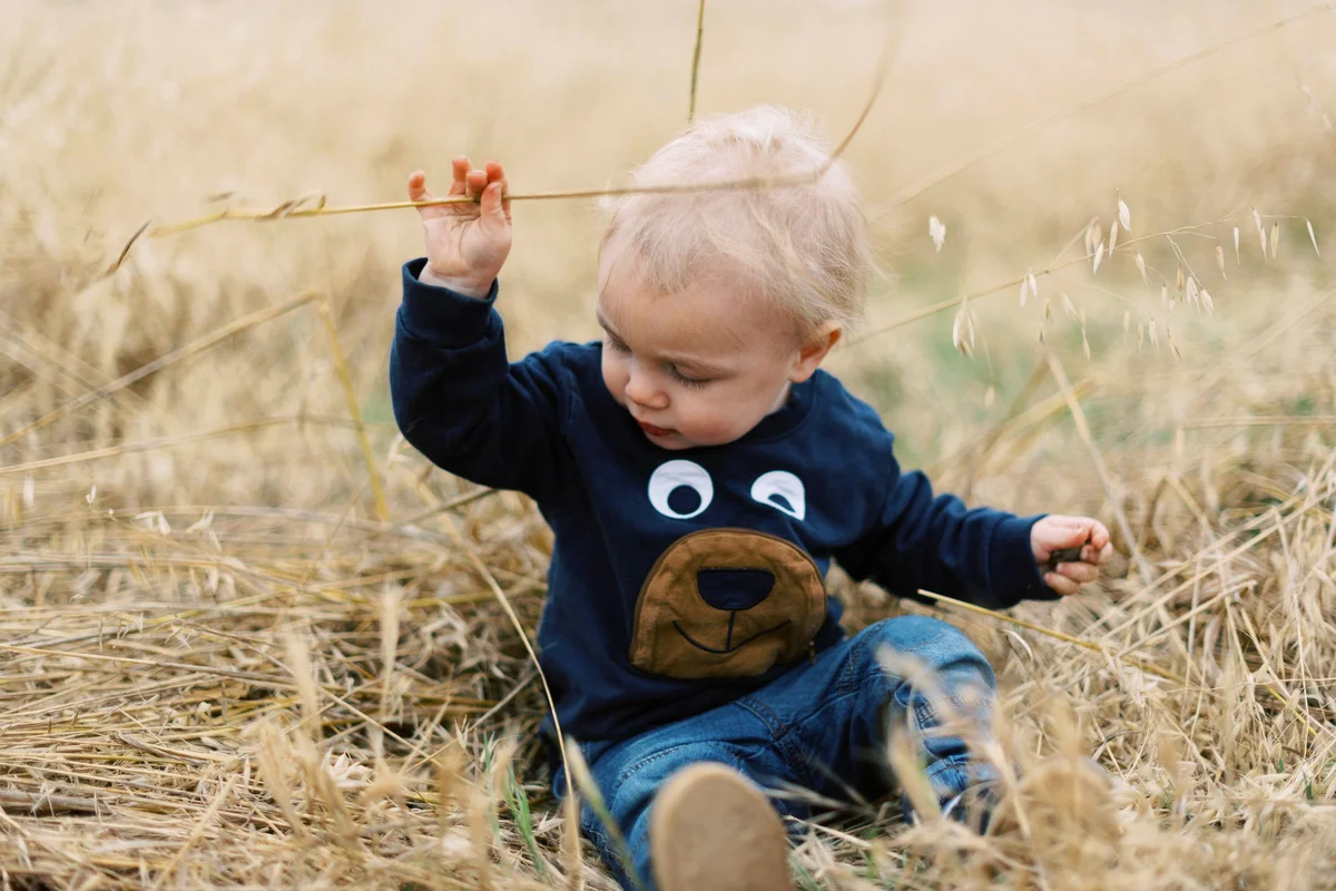 Little baby playing in dried grass in southern california in spring