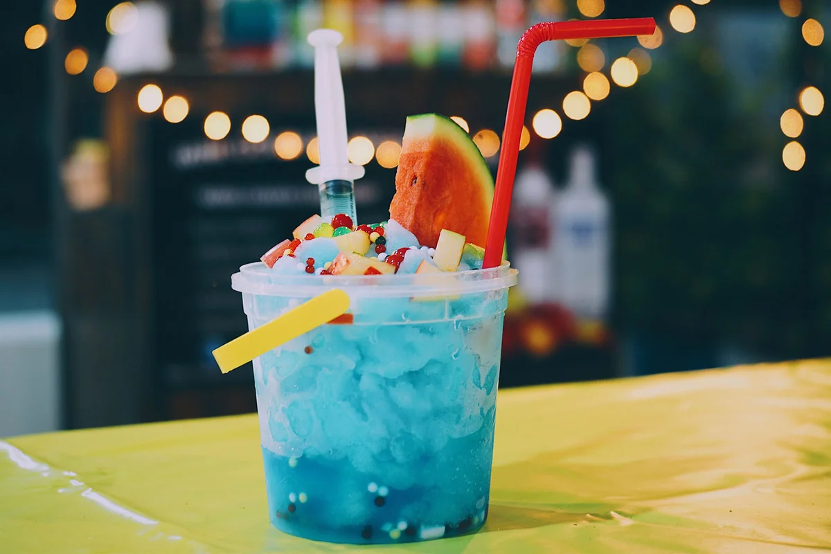 blue color fishbowl cocktail with watermelon garnish