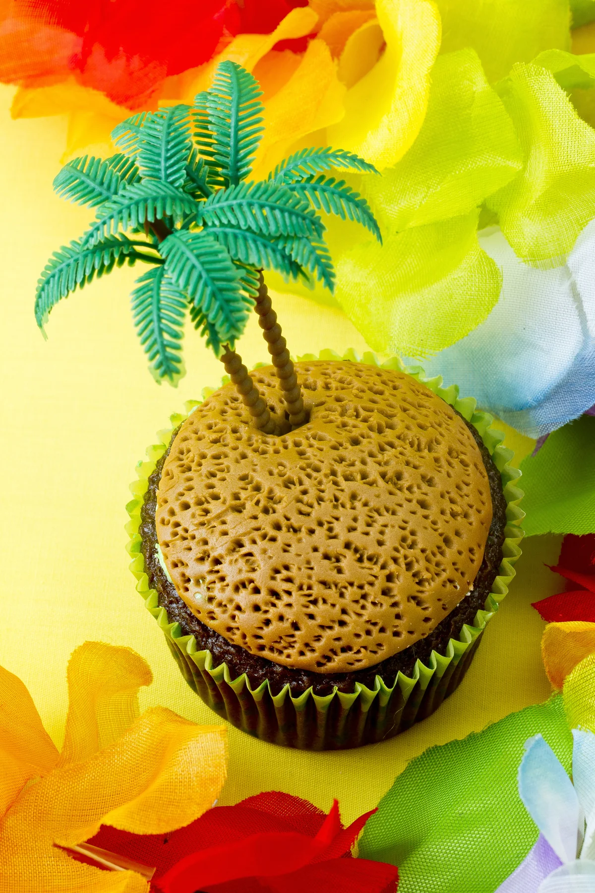 Cupcake with plastic coconut tree surrounded by flowers