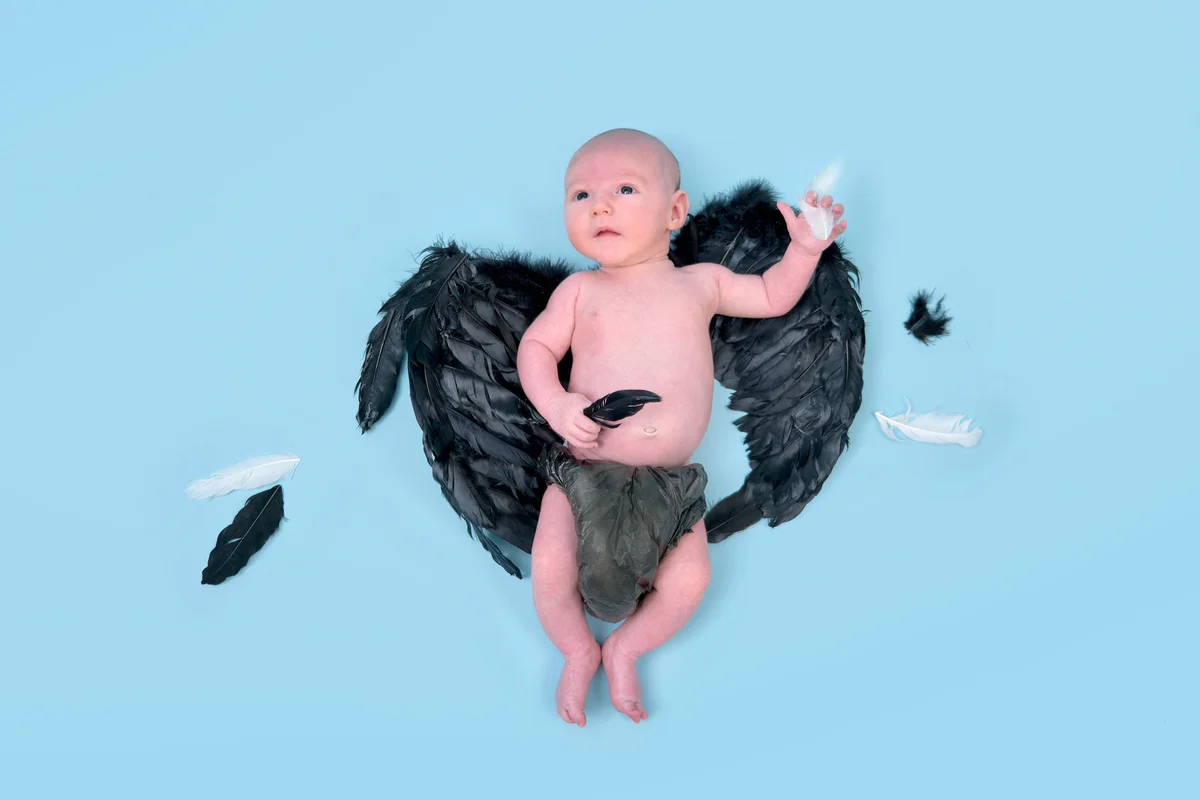Newborn baby boy with dark demon wings