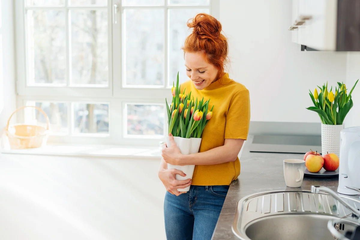 Smiling young woman standing and looking down at tulip bouquet