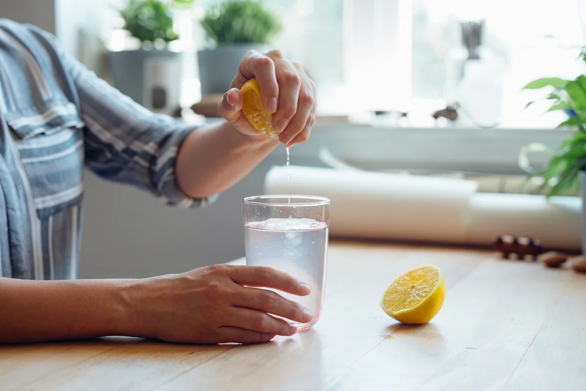 Young Woman Squeezing a Lemon into a Cup of Water