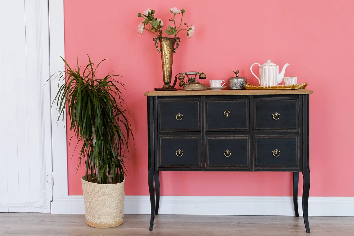 Old chest of drawers with objects on the background of a pink wall