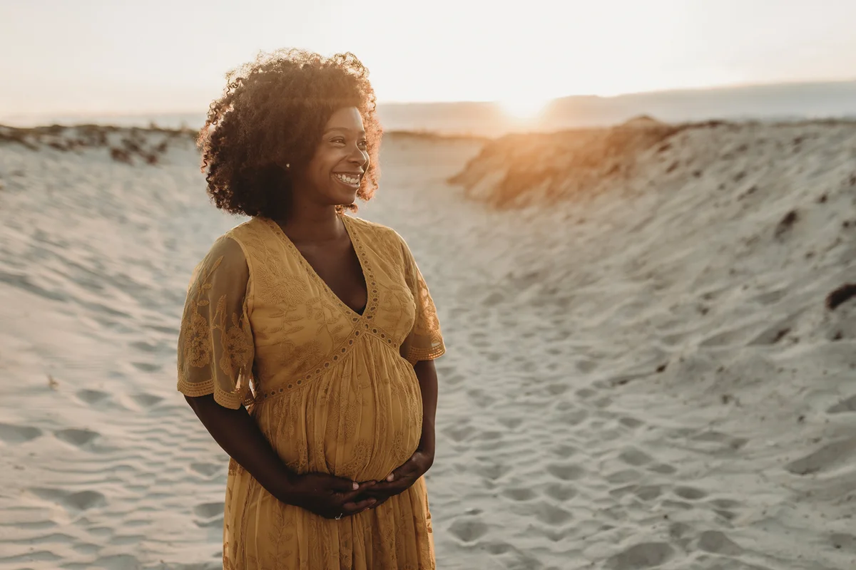 Portrait of pregnant mother in third trimester at beach at sunset