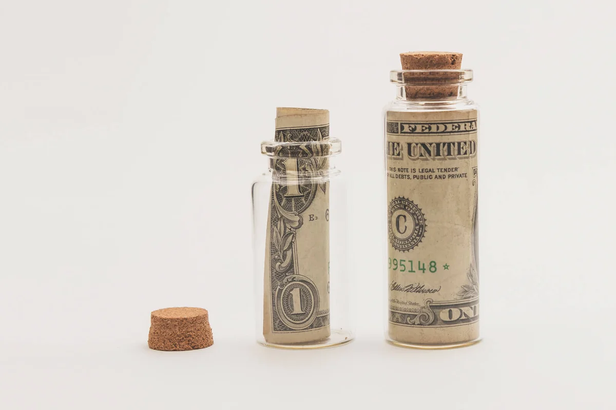 US paper currency in glass tubes over white background.