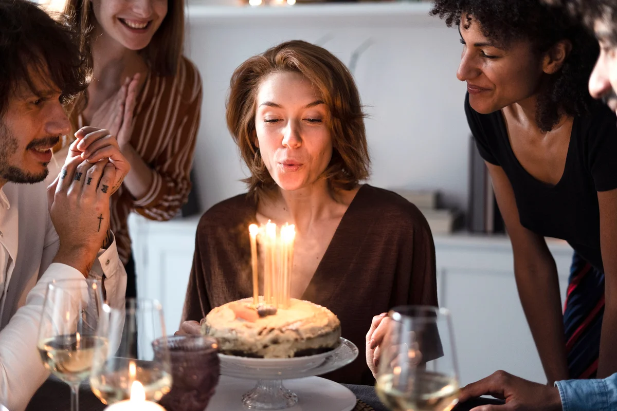 Woman with friends blowing out birthday candles