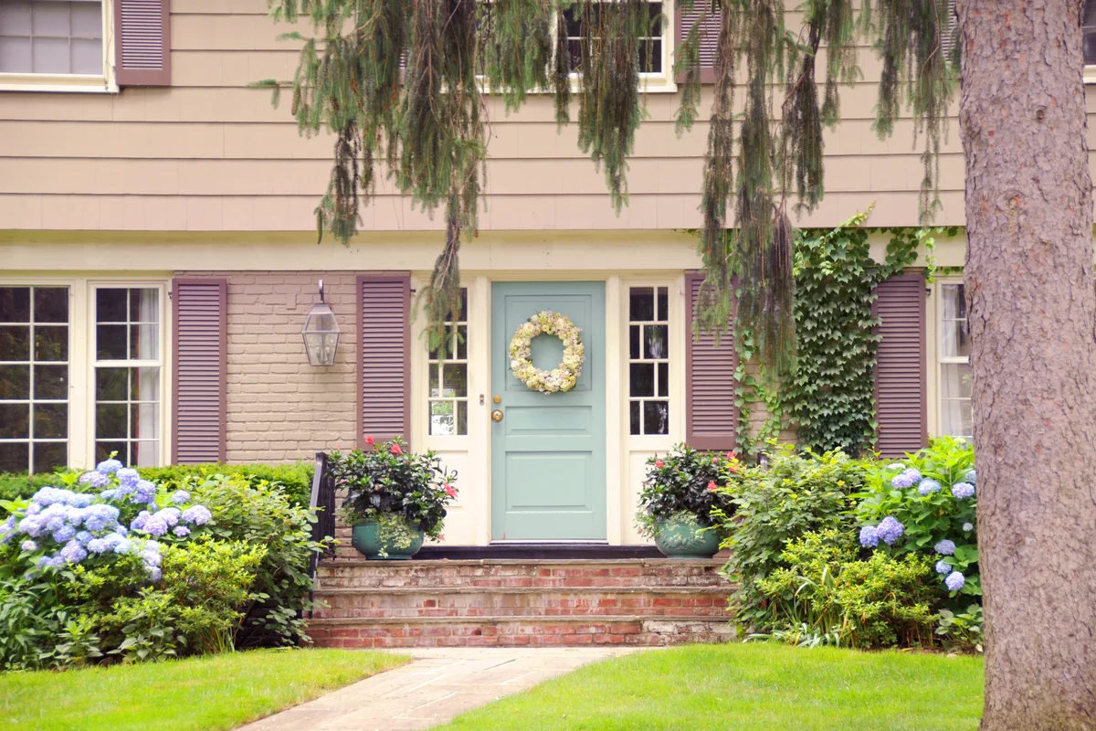 Colonial home with green door and lush greenery