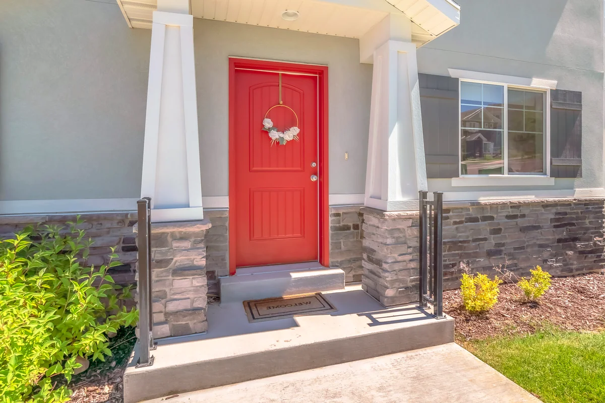 Red front door with pillars and railing on both sides