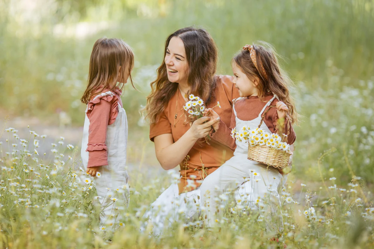 Happy mother and little girls picking flowers