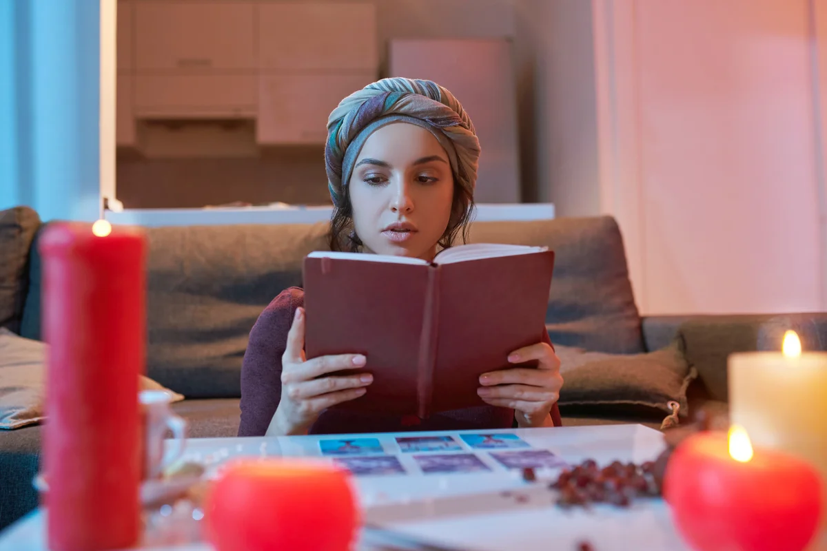 Beginner Tarot card reader in headwear reading a fortune-telling handbook