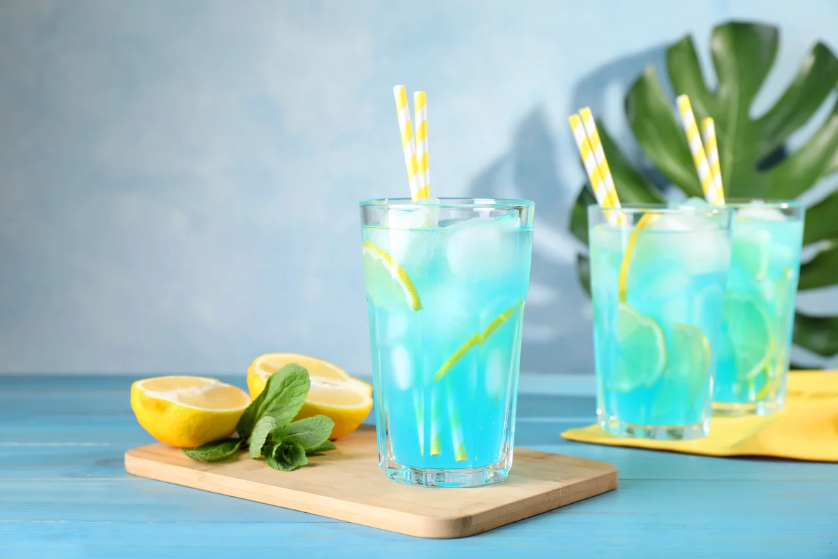 Refreshing blue cocktail with ice on wooden table