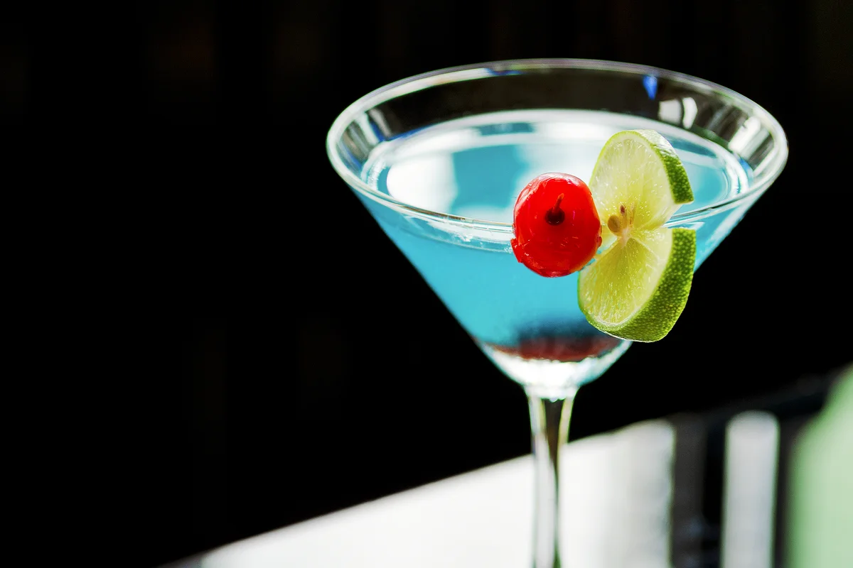 Blue cocktail with cherry and lime
