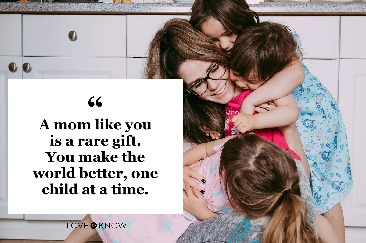 Young mother sitting on the floor in the kitchen, surrounded and hugged her young daughters