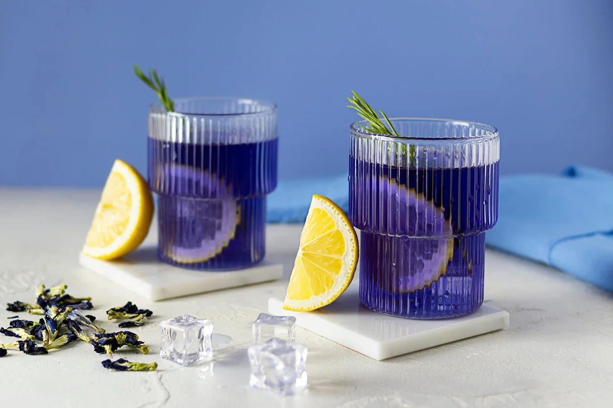 Two transparent glasses with blue cold tea from clitoria flowers