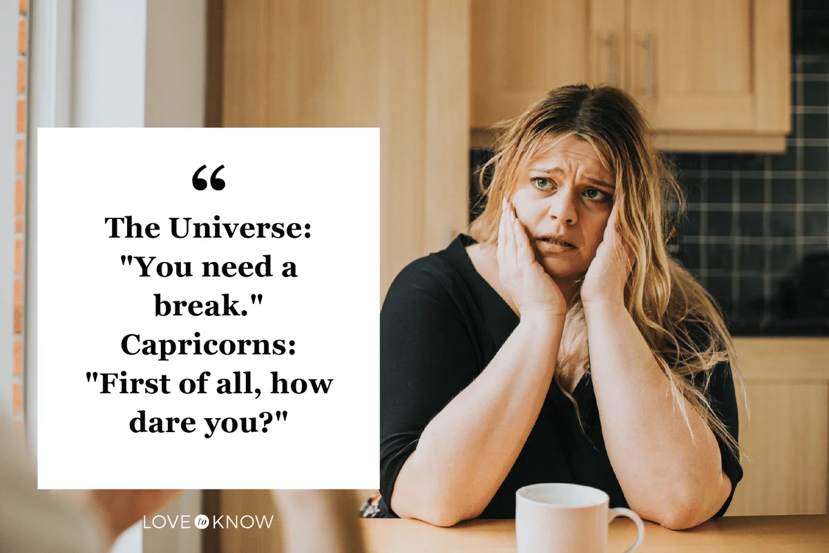 Worried woman sits at a kitchen table holding her head in her hands