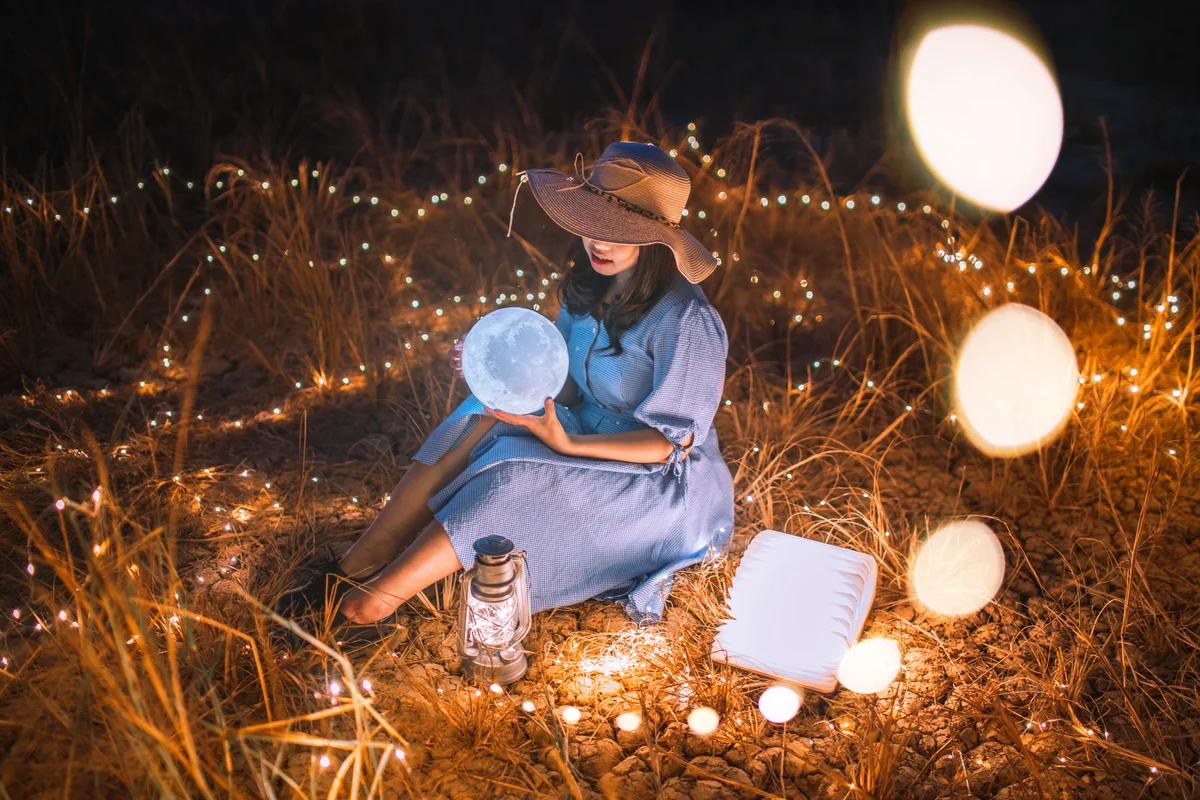 Woman in a field with the moon on her hand