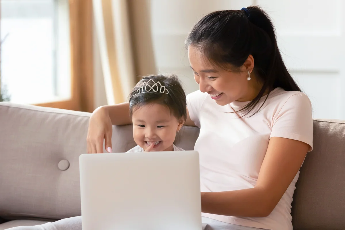 Young mother and little daughter using laptop together