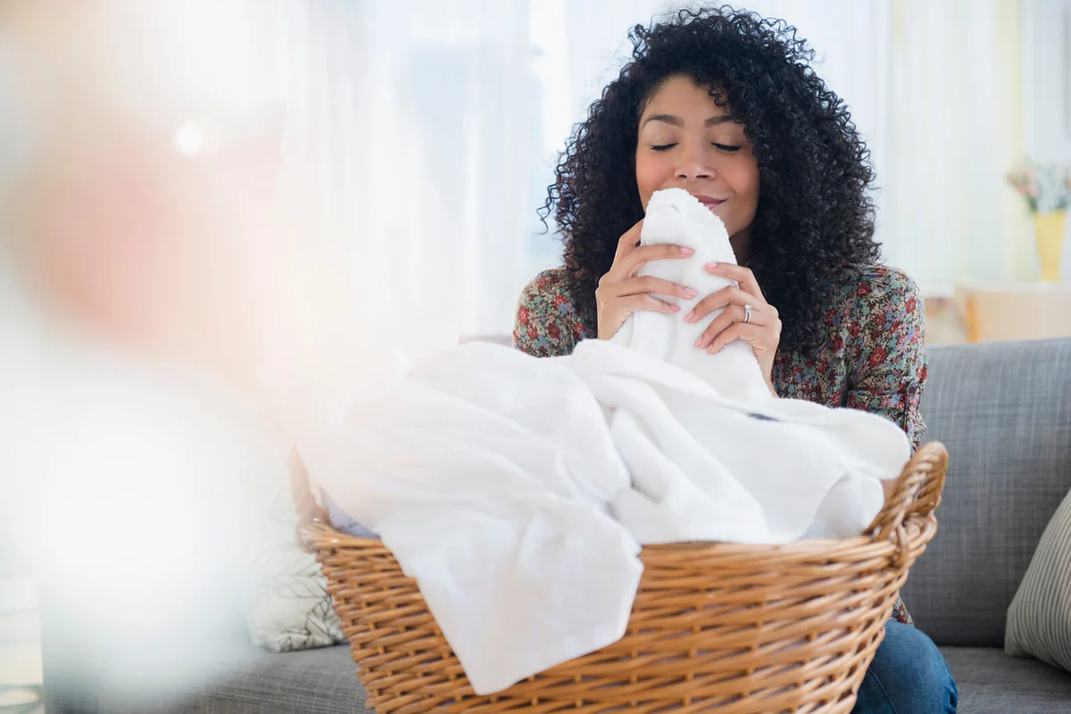 woman smelling clean towels in laundry