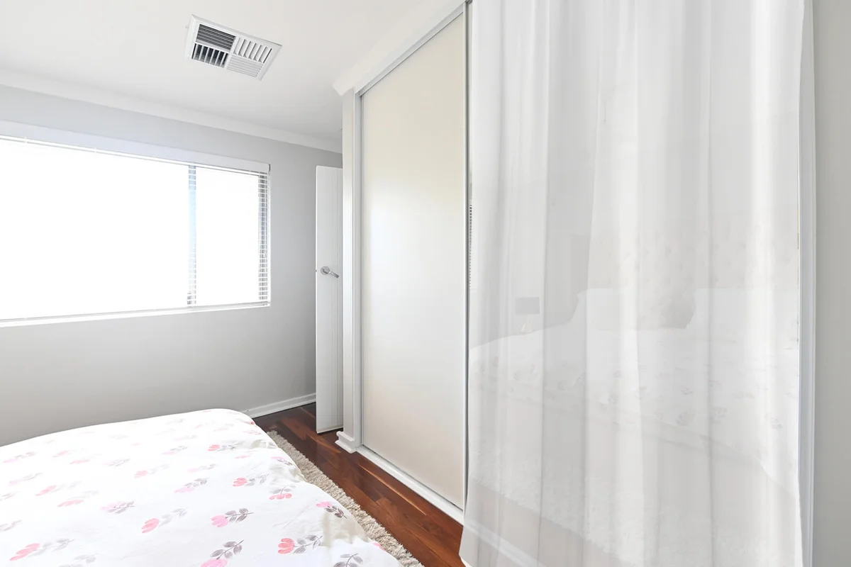 Empty double bed reflecting from a built-in wardrobe mirrow