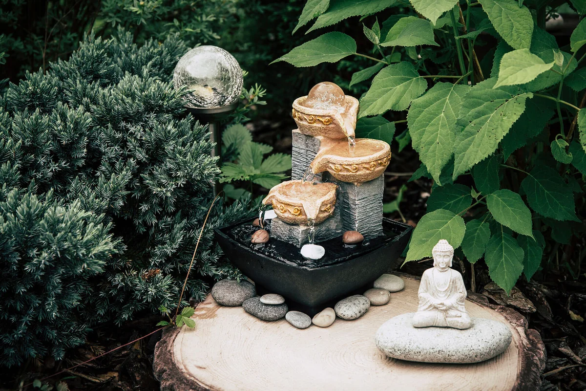 Small home garden private fountain with buddah statue between trees and bushes