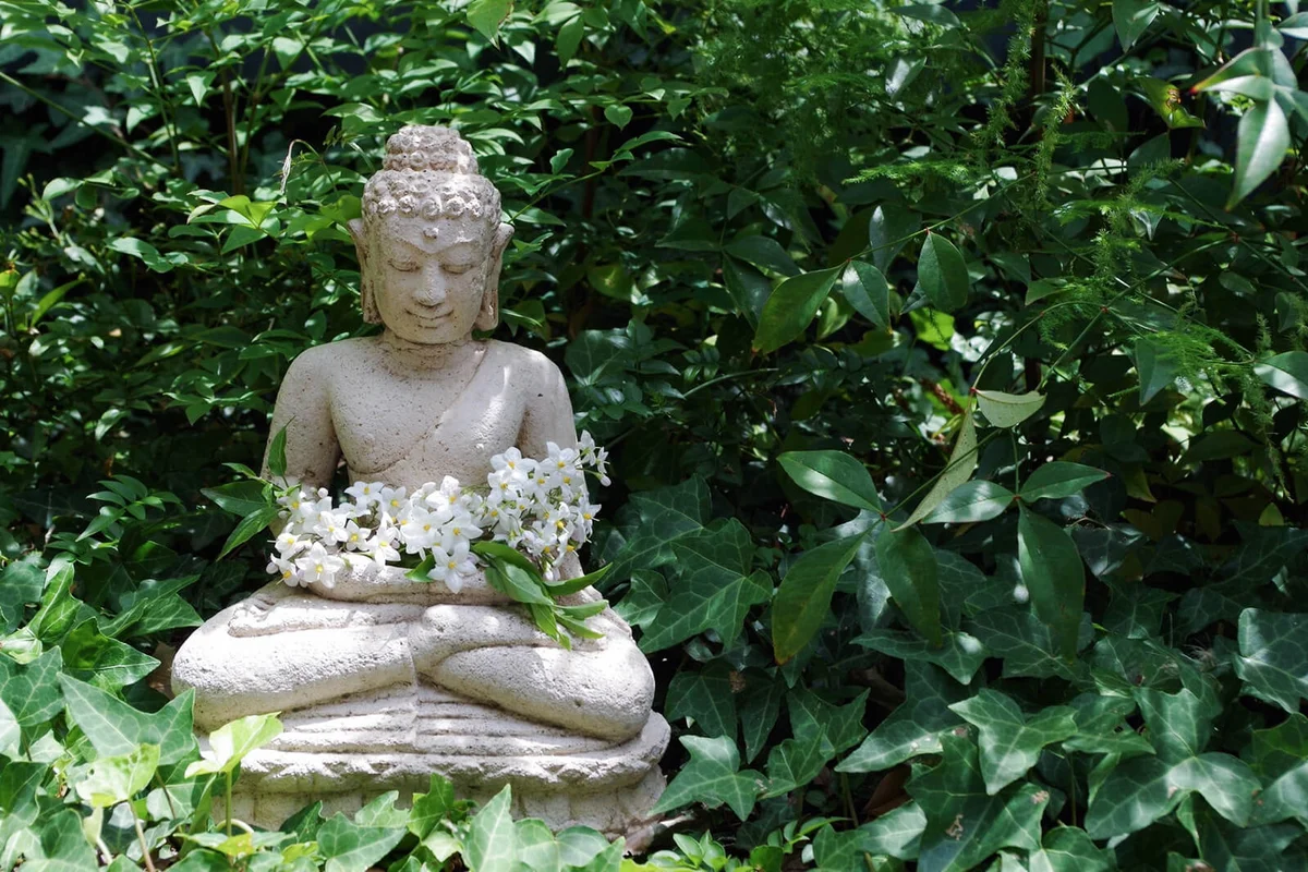 Buddha Statue With Flowers In Middle Of Plants