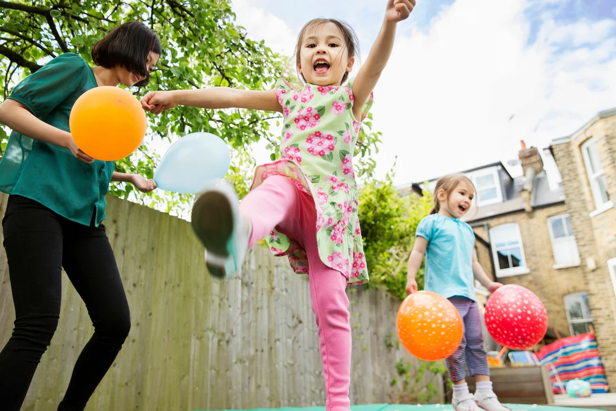 Mother and daughters playing in garden with balloons