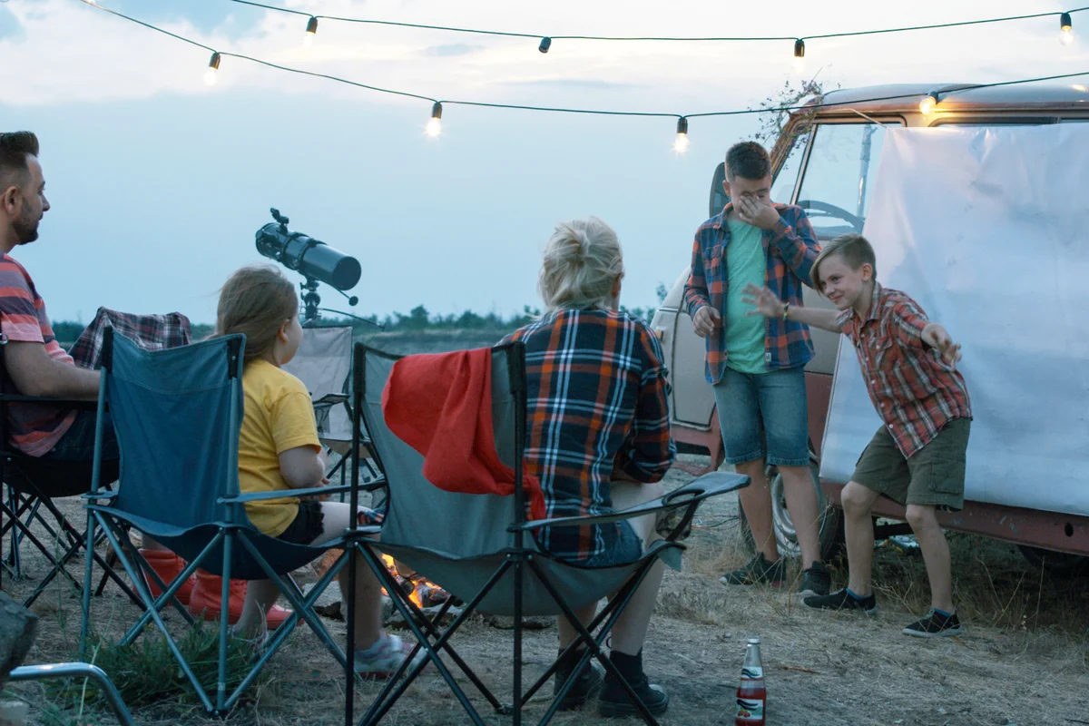 People with children playing charades in campsite