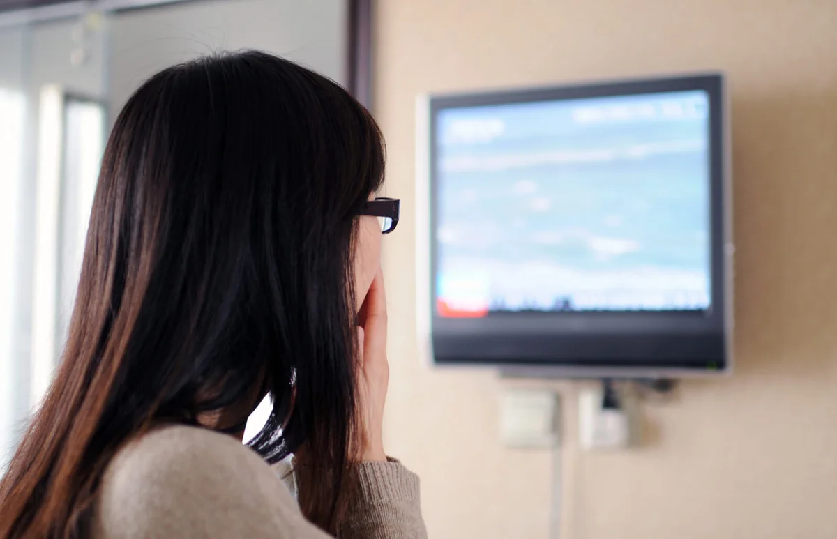 woman is watching news on TV