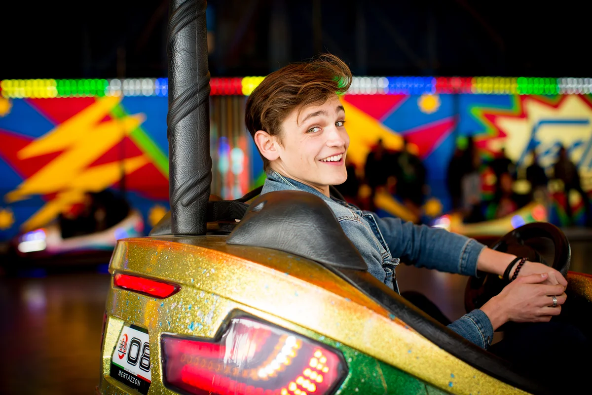 Teenage boy driving bumper car in amusement park