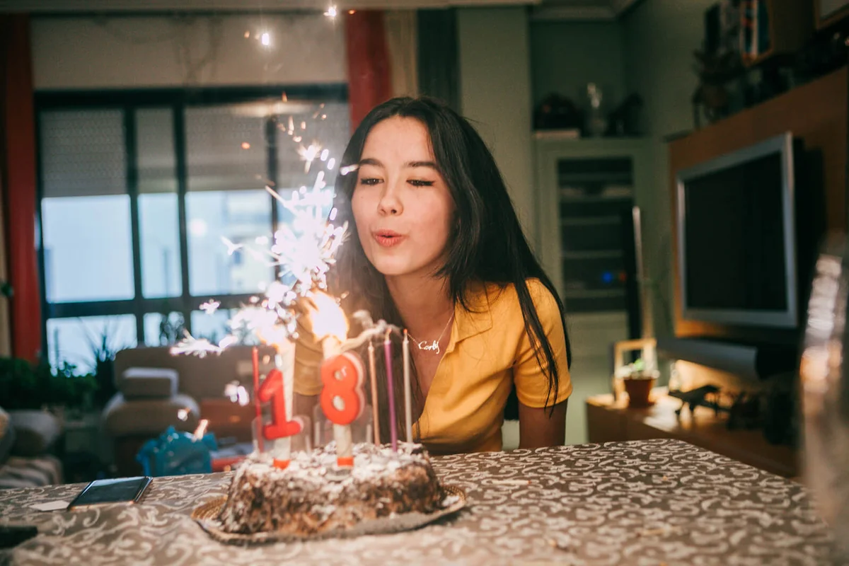 teenager girl blowing out candles in her birthday