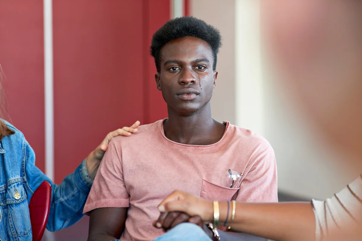 Sad young man being consoled by friends