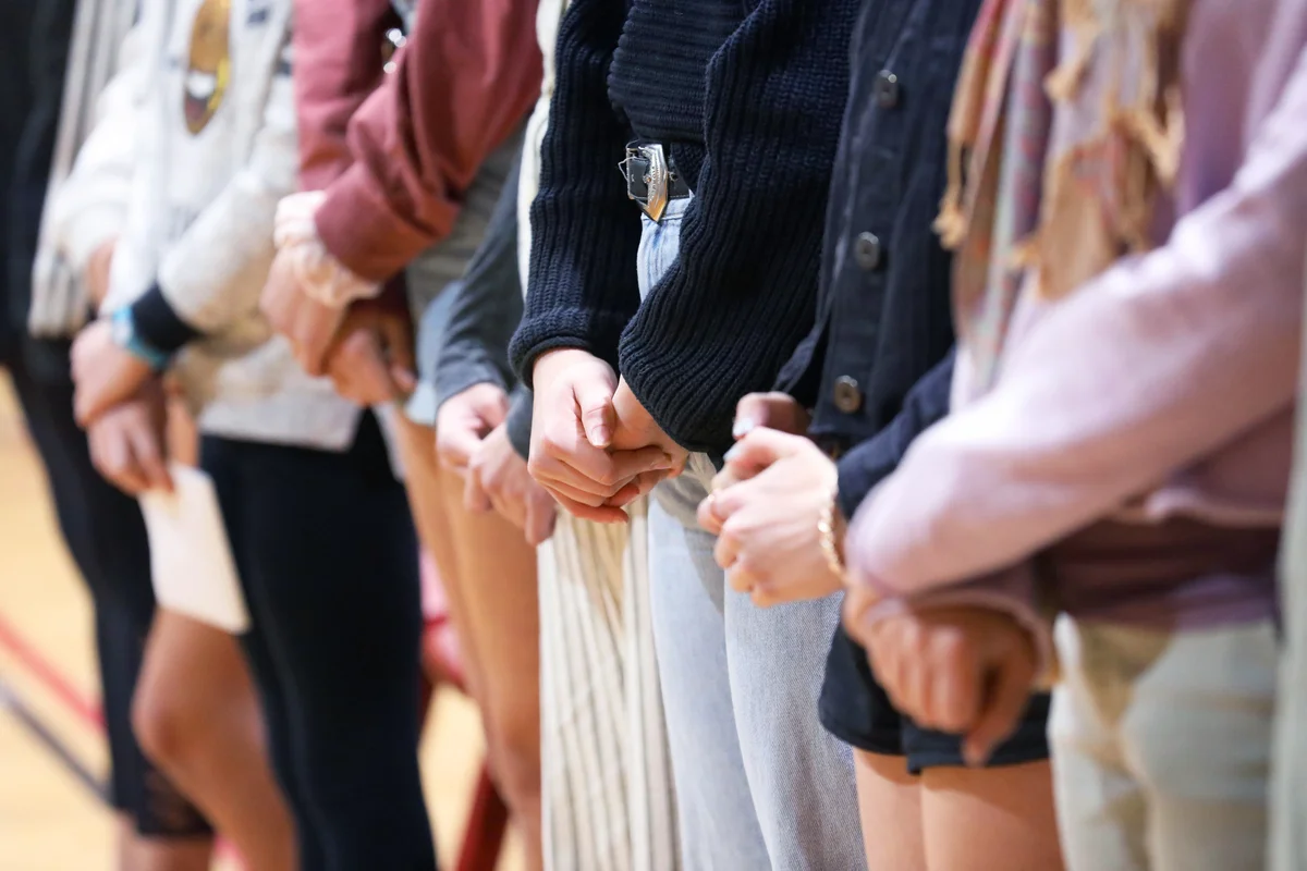 Row of people with hands folded standing together