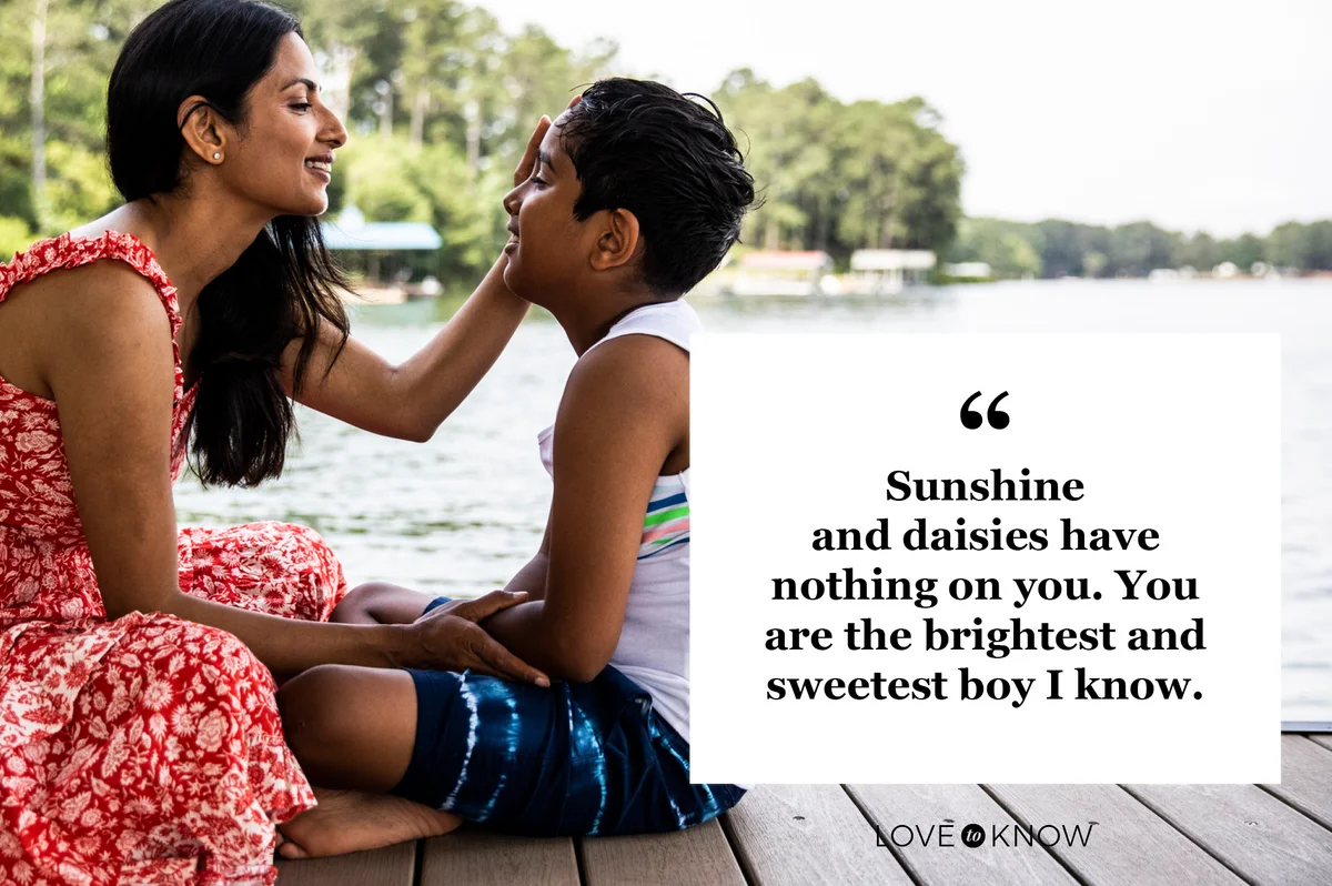 mother looking at son sitting on dock of lake