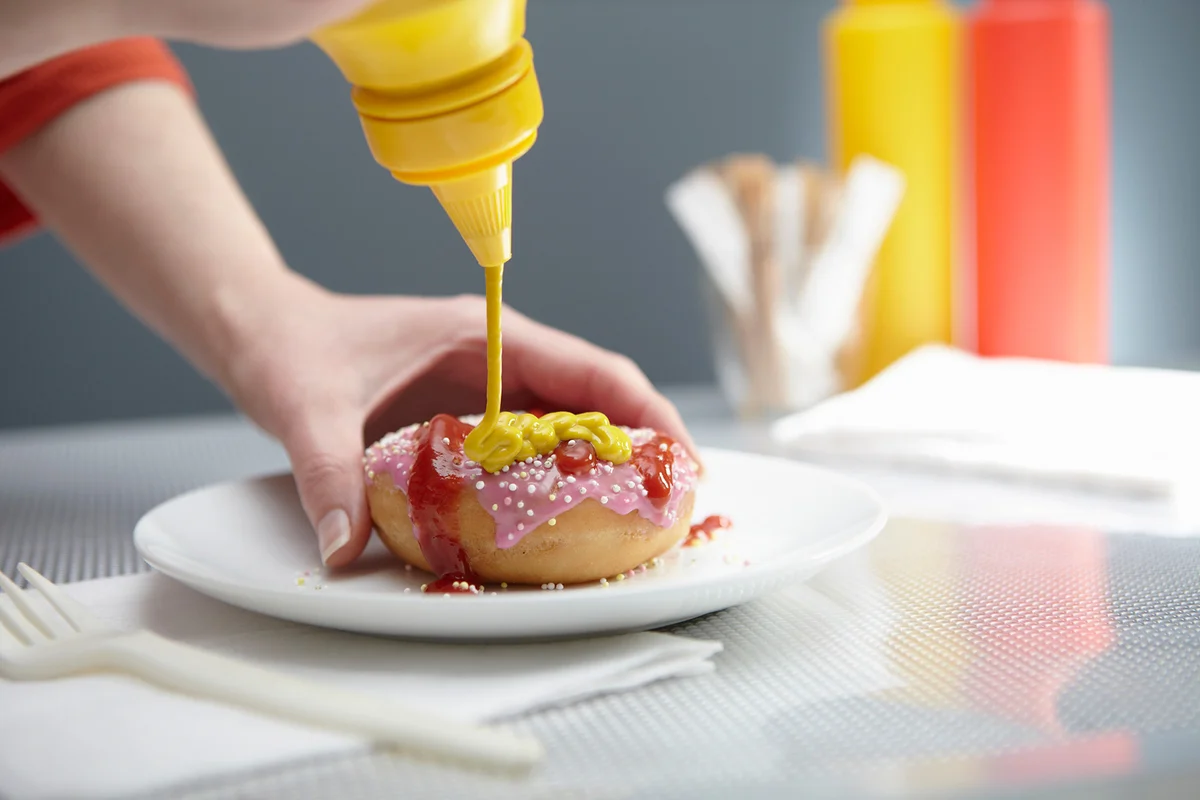 Woman squirting mustard on donut
