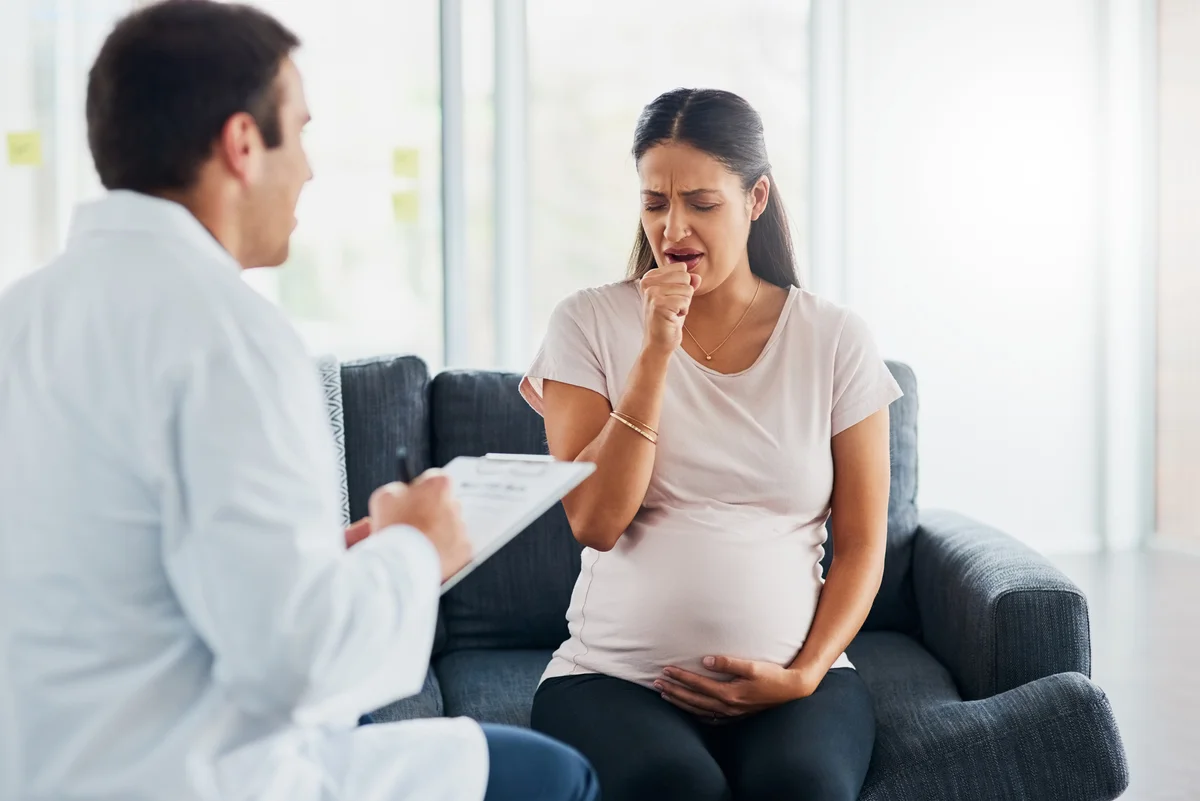 Pregnant woman coughing at doctor's office