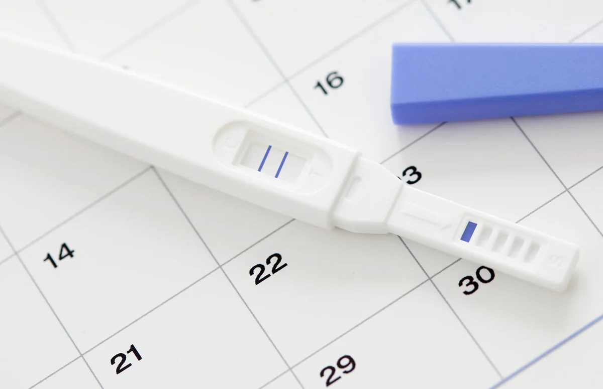 Pregnancy test showing positive result and calendar