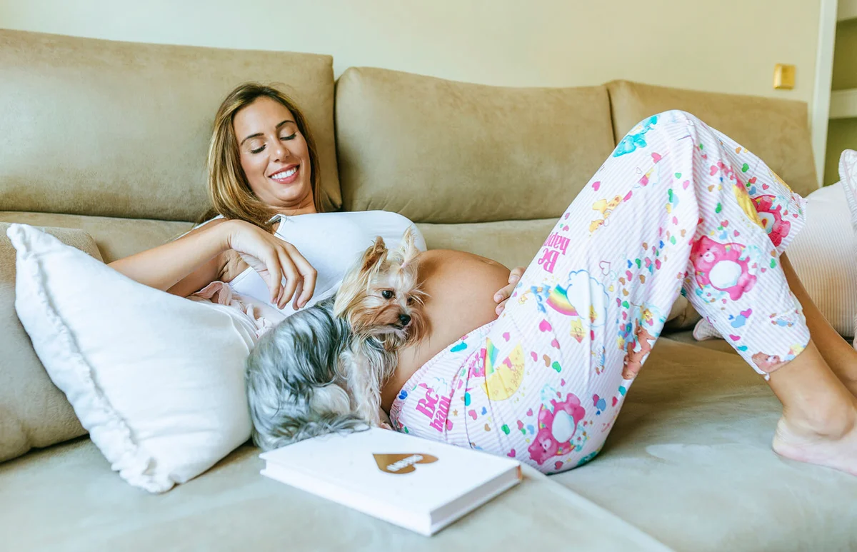 Pregnant woman and dog lying on the couch at home