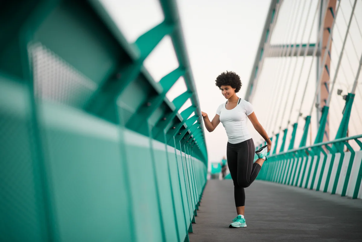 woman stretching on city bridge