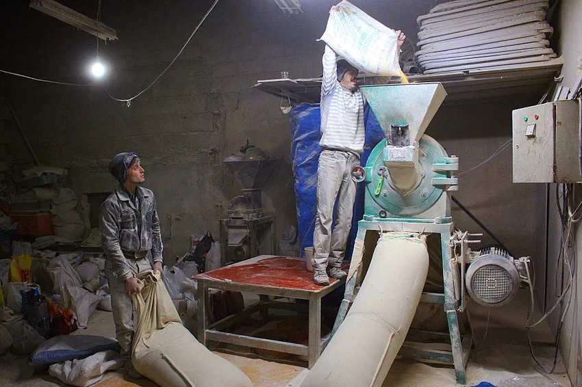 Men grinding barley flour with hammer mill