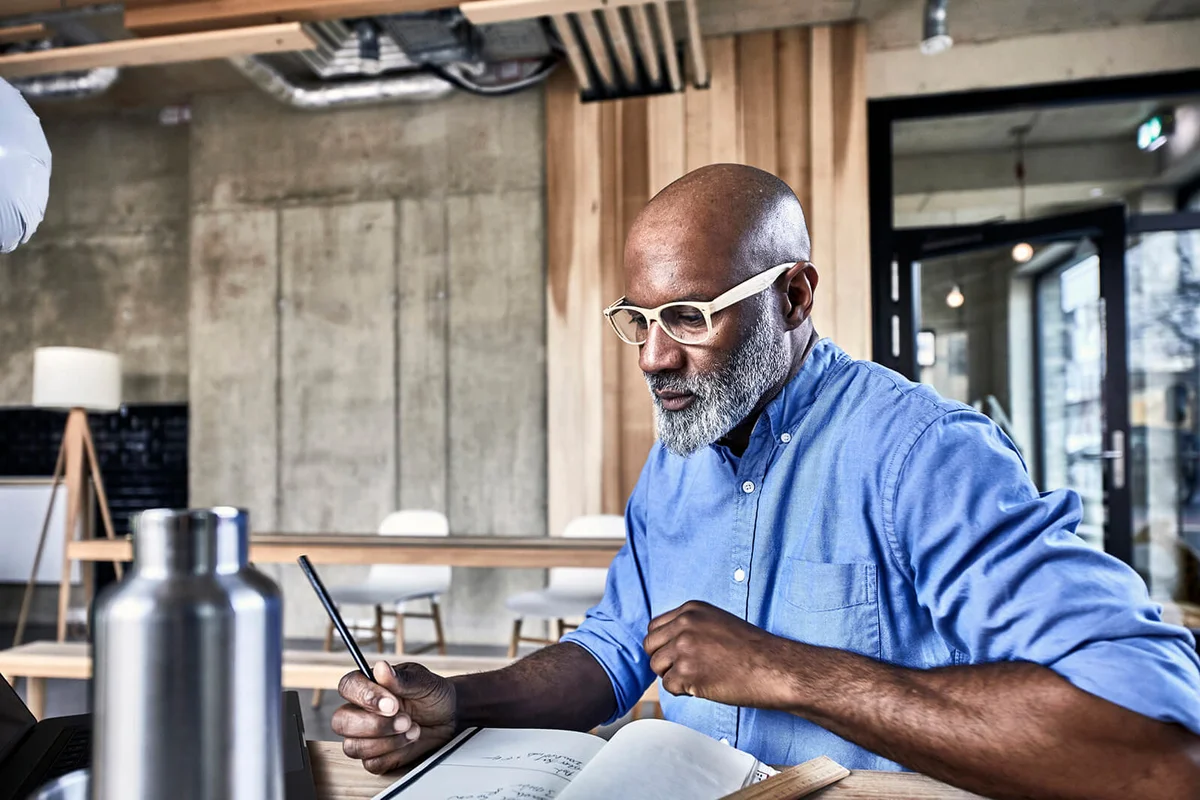 Mature businessman in modern office taking notes