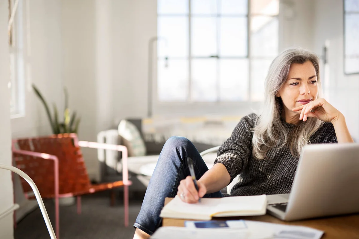 Mature woman writing in diary while working at home