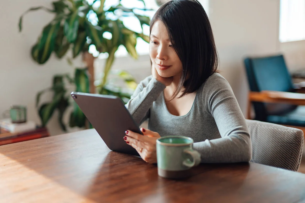 Young woman reading news and e-book on digital tablet
