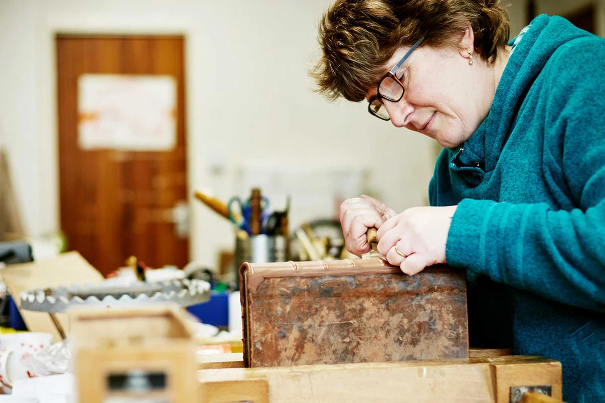woman binding an antique book for restoration