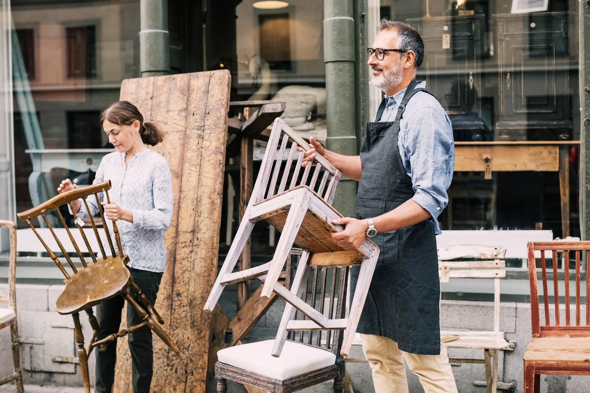 man setting up wooden chairs at antique shop