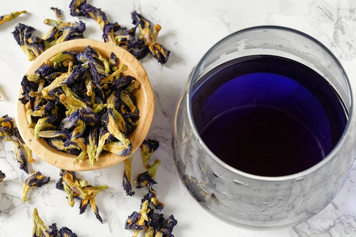 Butterfly pea flowers next to a glass